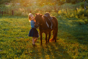 A girl and a pony outside at sunset. Nature near the water