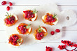 Holiday crostini appetizers with cranberries, brie and caramelized onions. Above table scene on a white platter.