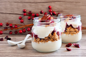 Wall Mural - cranberry granola parfaits in mason jars on a rustic wood background