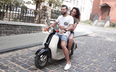 Canvas Print - Cheerful young couple riding a scooter and having fun