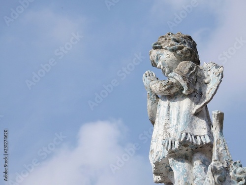 Fotografering Stone statue of a little angel with wings, praying