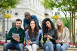 © javiindy - Multi-ethnic young people using smartphone and tablet computers outdoors