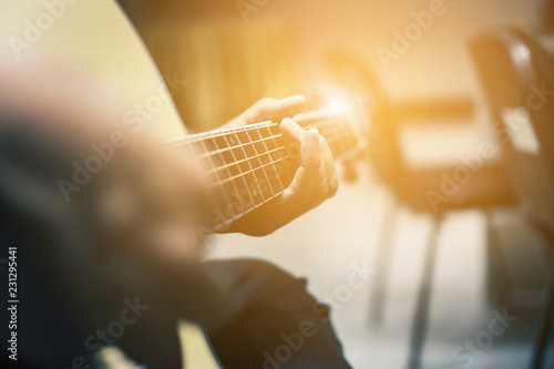 Fotografia, Obraz The man is playing guitar in the garden, Close-up male hand playing on acoustic guitar outdoor with bokeh and rays of sunlight