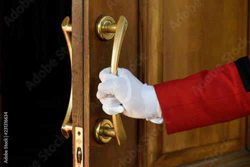 the doorman opens the hotel door hands in white gloves