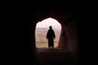MAN WITH TUNIC AND PALESTINIAN SCARF IN A CAVE LOOKING A VALLEY