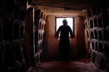 MAN WITH TUNIC AND PALESTINIAN SCARF IN A OLD CAVE LOOKING FOR A WINDOW