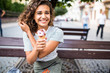 © F8  \ Suport Ukraine - Young latin curly woman sitting on a park bench and eating ice cream in the summer