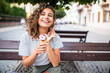 © F8  \ Suport Ukraine - Young latin curly woman sitting on a park bench and eating ice cream in the summer