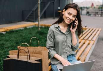 Sticker - Cheerful happy businesswoman with beautiful smile wearing stylish clothes using laptop computer and mobile phone for online shopping. Discount sales. Portrait of successful entrepreneur working online