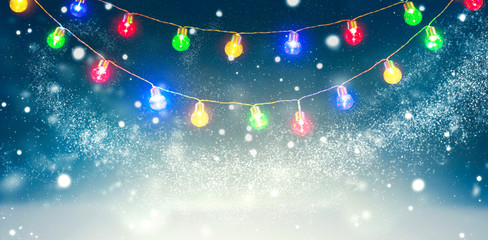 Wall Mural - winter holiday snow background decorated with colorful light bulbs garland. snowflakes. christmas an