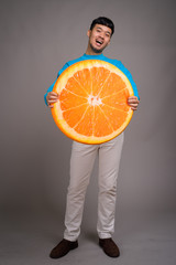 Wall Mural - Portrait of young Asian man holding big slice of orange