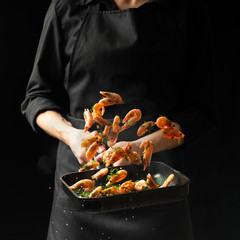 Professional chef prepares shrimps with greens.