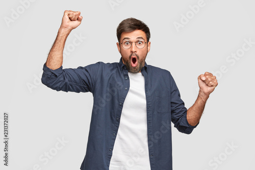 Cuadros en Lienzo Waist up shot of emotive Caucasian man has surprised facial expression, raises h