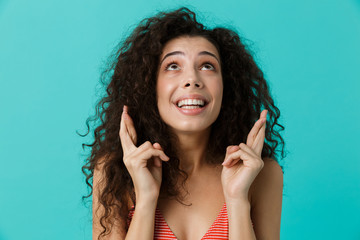 Sticker - Image of delighted woman 20s wearing casual clothing holding fingers crossed, standing isolated over blue background