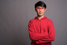 Young Asian Man Wearing Red Jacket With Eyeglasses Against Gray 