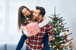 © baranq - Cheerful couple holding present and goofing around in christmas decorated living room