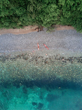Aerial View Of A Beach Near A Forest With Red Canoes