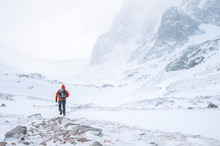 Climber Walks Alone In High Mountains At Windy Snowy Weather