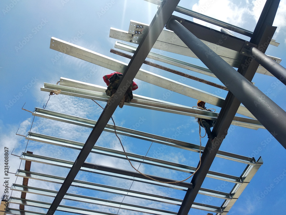 Construction workers installing metal roof trusses at the construction ...