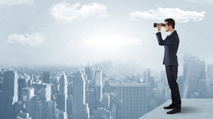 Wall Mural - businessman looking forward to a city with binoculars from skyscraper concept