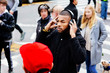 © Carlos David - Portrait of a young man listening and holding headphones while crossing the street amongst crowd