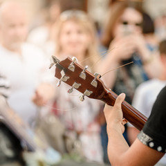 Closeup photo of busker plaing guitar on city street