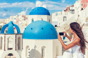 Fototapete - Travel tourist taking phone picture of Santorini Blue dome church, touristic attraction in Europe, European vacation banner. Woman taking smartphone photo of famous destination.