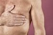 © Dmitry_Tkachev - Man suffering from chest pain, having heart attack or painful cramps, pressing on chest with painful expression on pink backgound. Severe heartache