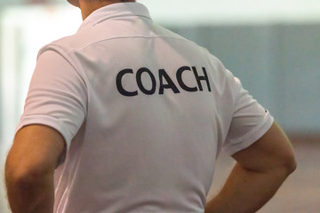 back view of male sport coach with word coach written on back of his shirt