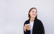 © bodnarphoto - Happy young woman in a business suit standing with a cup of coffee in her hands on a white background and smiling.Portrait of a girl with a glass of coffee in her hands, isolated on a white background