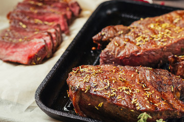 Wall Mural - Grilled beef steak on frying pan, top view. Fried chunks of meat close up