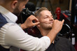 © serhiibobyk - Man during procedure of threading beard in barber shop