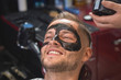 © serhiibobyk - Closeup of happy man with black mask on face in barber shop