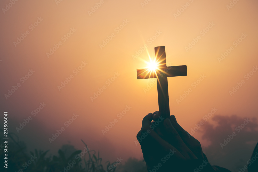 Silhouette of cross in human hand, the background is the sunrise., Concept for Christian, Christianity, Catholic religion, divine, heavenly, celestial or god. - obrazy, fototapety, plakaty 