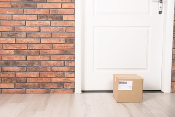 Poster - Cardboard parcel box on floor near apartment entrance. Mockup for design