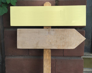 Two signs on a wood post with a brick background and copy space for your own message.