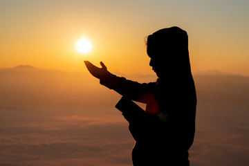 Wall Mural - Girl teen silhouette with her hands raised in the sunrise