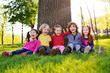 © Evgeniy Kalinovskiy - group of happy little children smiling sitting in park on grass under a tree. June 1, Children's Day, friendship, childhood, vacation.