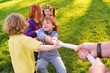 © Evgeniy Kalinovskiy - a group of small preschool children play a tug of war in the park. Outdoor games, childhood, friendship, leadership, children's day.