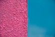 Full frame view of a rough textured bright pink and smooth blue divided wall