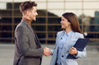 © Goran - Cheerful young businesswoman shaking hands with her male colleague