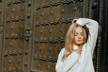 Closeup portrait of tender model with natural makeup posing near metal wrought door.  Space for text