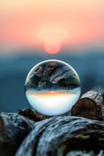 Scenic Autumn Sunset In Caucasus Mountains Viewed Through Glass Ball Lying On Wood Pile. Vertical Scenery With Blurred Background