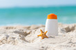 Protective sunscreen or sunblock and sunbath lotion in white plastic bottles with sandals on tropical beach, summer accessories in holiday, copy space.  Summer Concept