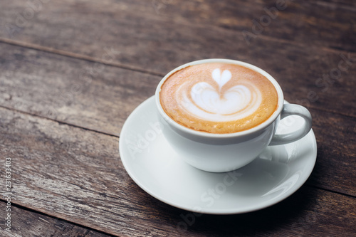 Fotomural Close up white coffee cup with heart shape latte art on grunge wood table at cafe