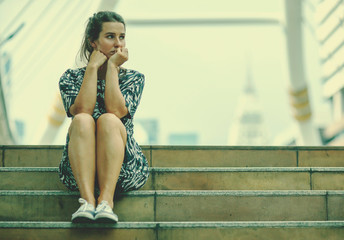 alone woman and depressed sitting on stair walkway of downtown with The pale sky lonely scene, waiting for hope,sad mood,feel tired and unhappy. copy space