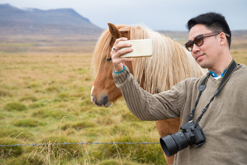 A man tourist took photo together with an Icelandic horse