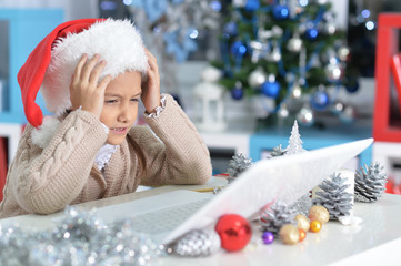 Wall Mural - Little girl in Santa hat with laptop