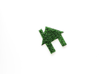 Green eco energy concept. House silhouette made of green grass on white background top view copy space