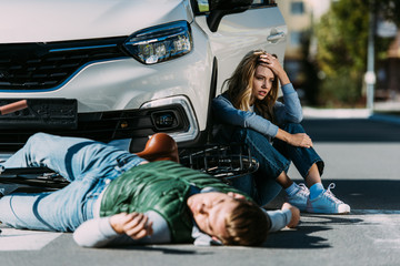 Wall Mural - woman sitting near car while injured cyclist lying on road after traffic collision